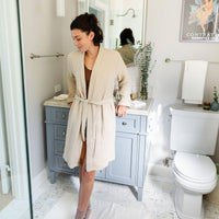 Unisex Turkish Cotton Robe, woman lounging in Bone. Lightweight and Absorbent Turkish Cotton Towels. Luxuriously Soft and Eco-Friendly.