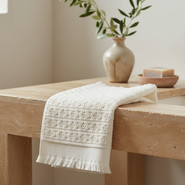 White fringed bath mat with a vase and plant in the background