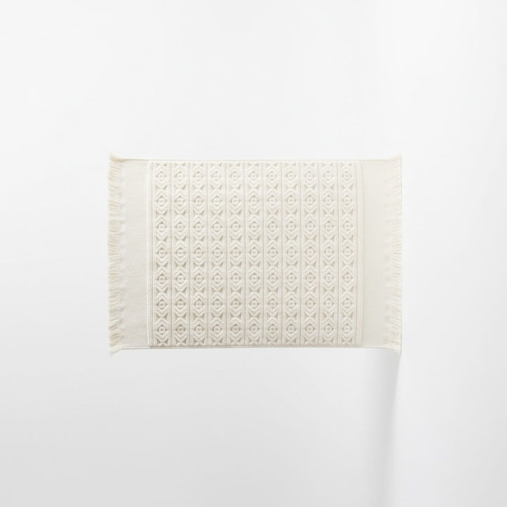 White bath mat with a subtle pattern on a white background
